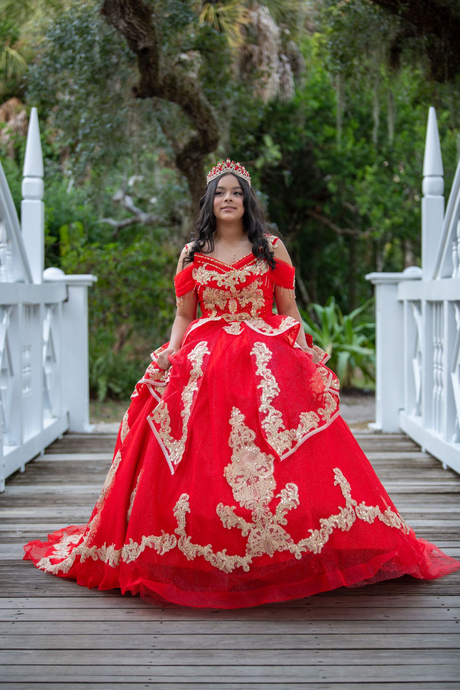 Quinceañera photos on white bridge showing full red and gold princess dress.