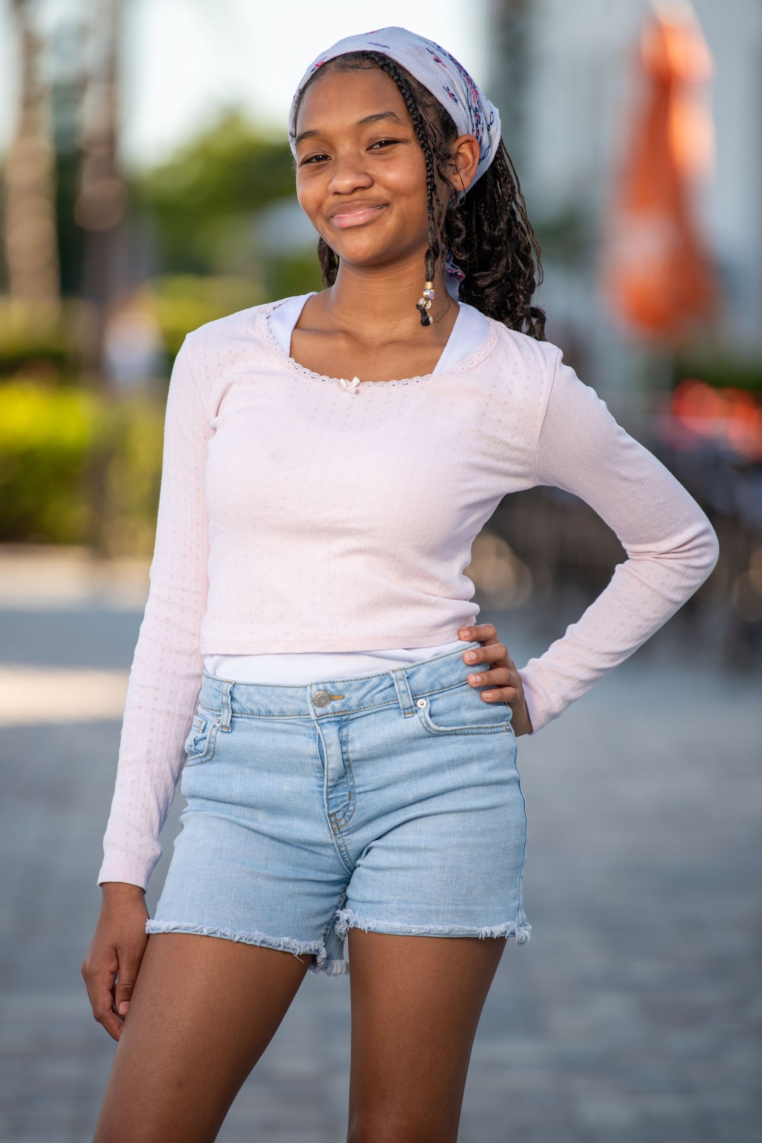 Summer fashion portrait in denim shorts and white top against tropical background. Headshots.