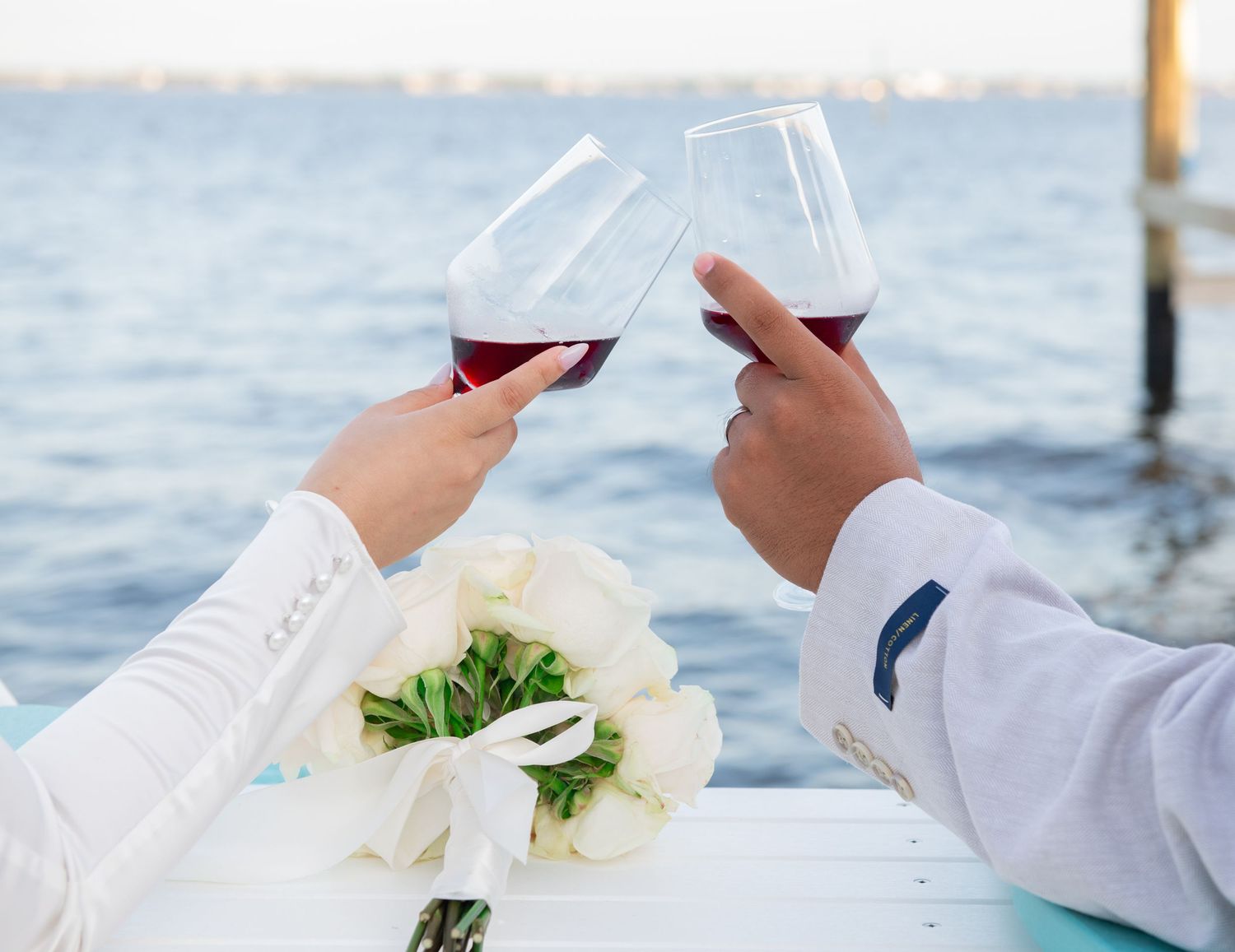 Wedding couple reading documents by the waterfront in white attire.