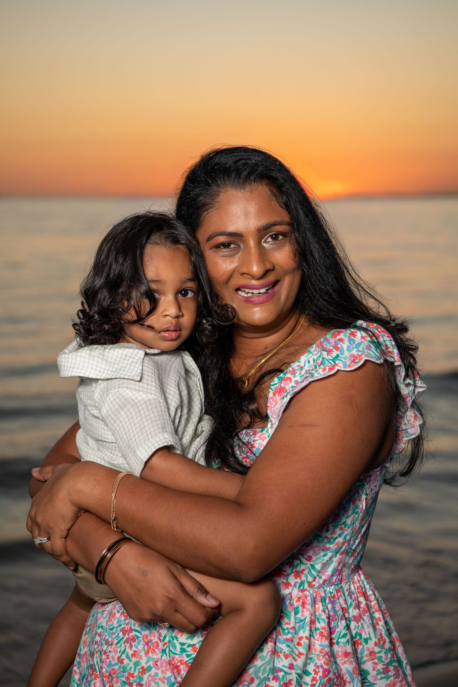 Candid family moments captured during sunset at the beach with warm orange tones. Beach photoshoot. Family photoshoot,