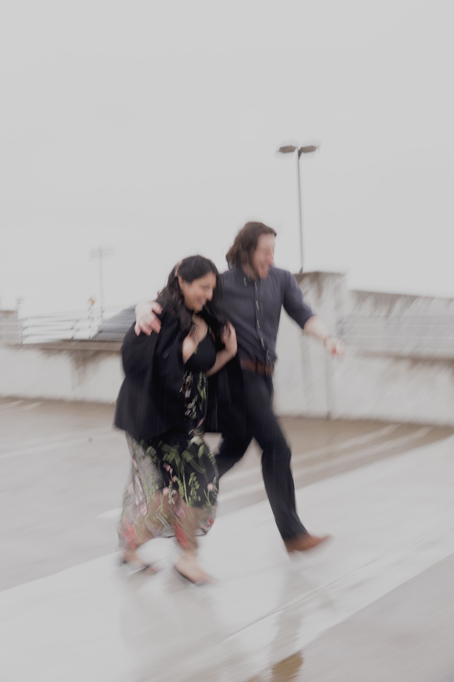 running through the rain during a photoshoot with your love on top of a parking garage in Sacramento California