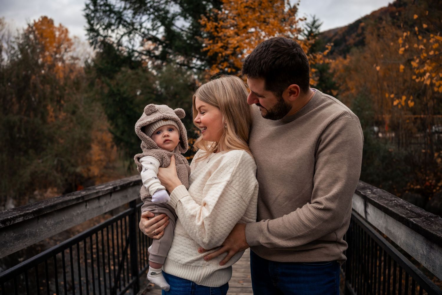 Photo d’un bébé et de ses parents en extérieur, Mont-Saint-Hilaire, lumière douce et tendresse partagée.
