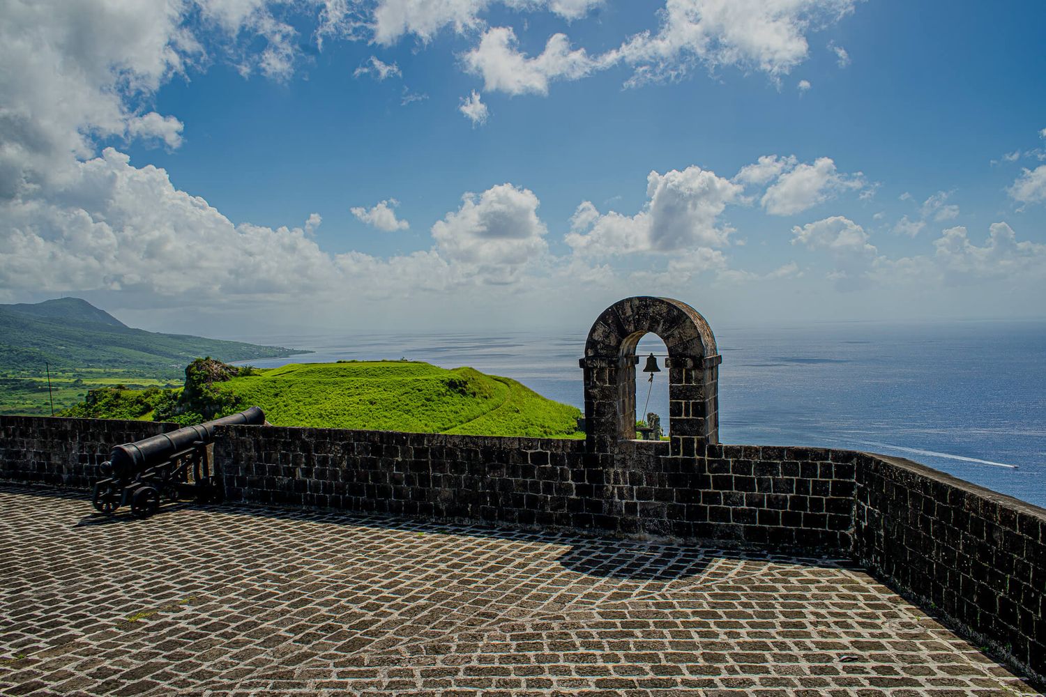 Panoramic view of Brimstone Hill Fortress walls and turrets overlooking the Caribbean Sea on a sunny day.