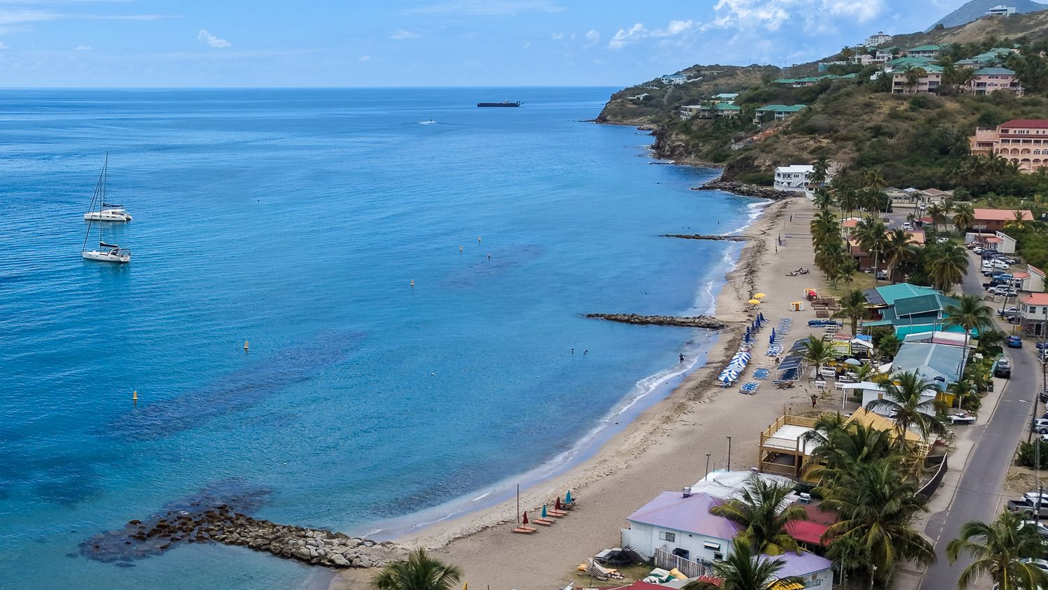 Frigate Bay Beach Photos - Is it onAerial view of a tropical beach with turquoise waters, boats, and colorful buildings along the coastline.