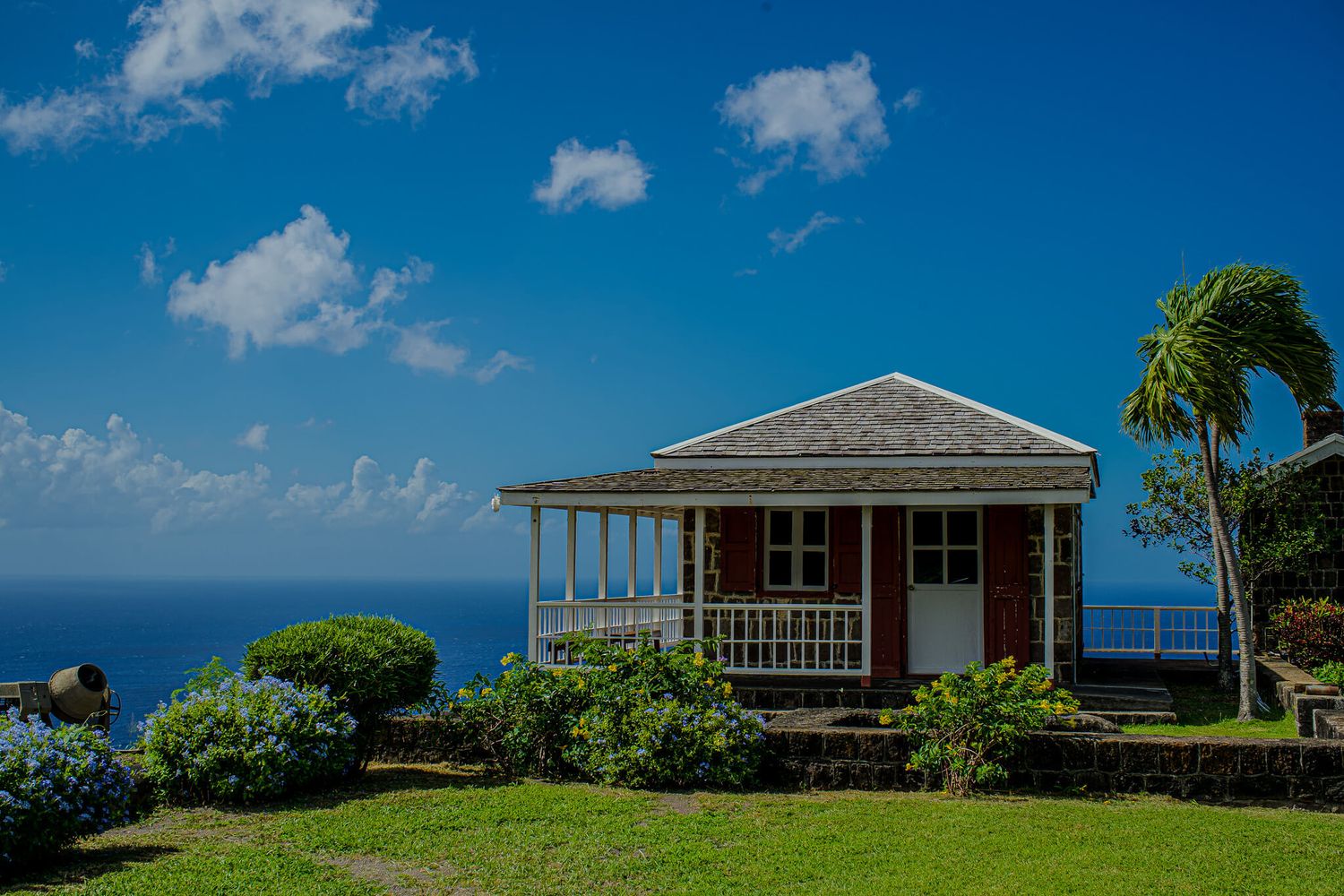 A panoramic view of coastal homes with blue skies, white clouds, and tropical palm trees along the oceanfront.
