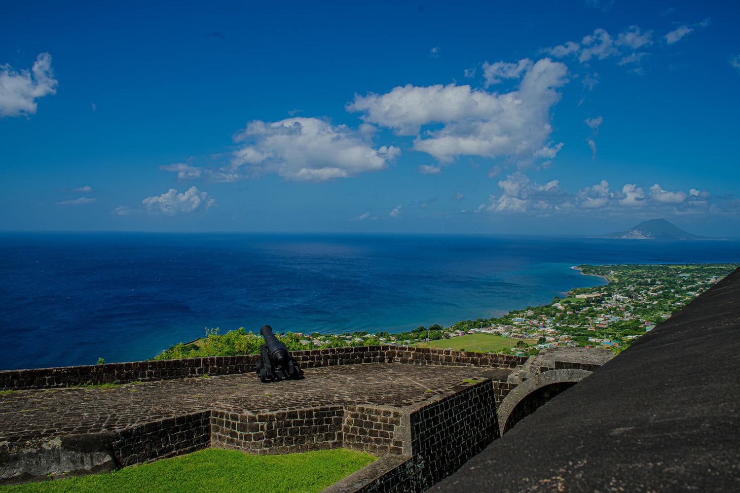 Historic stone fortifications of Brimstone Hill Fortress overlook the Caribbean Sea against a bright blue sky in St Kitts.