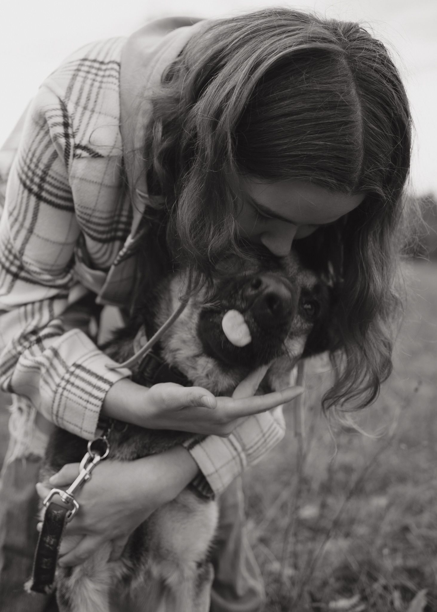 Black and white photos showing someone petting and bonding with their dog in a field.
