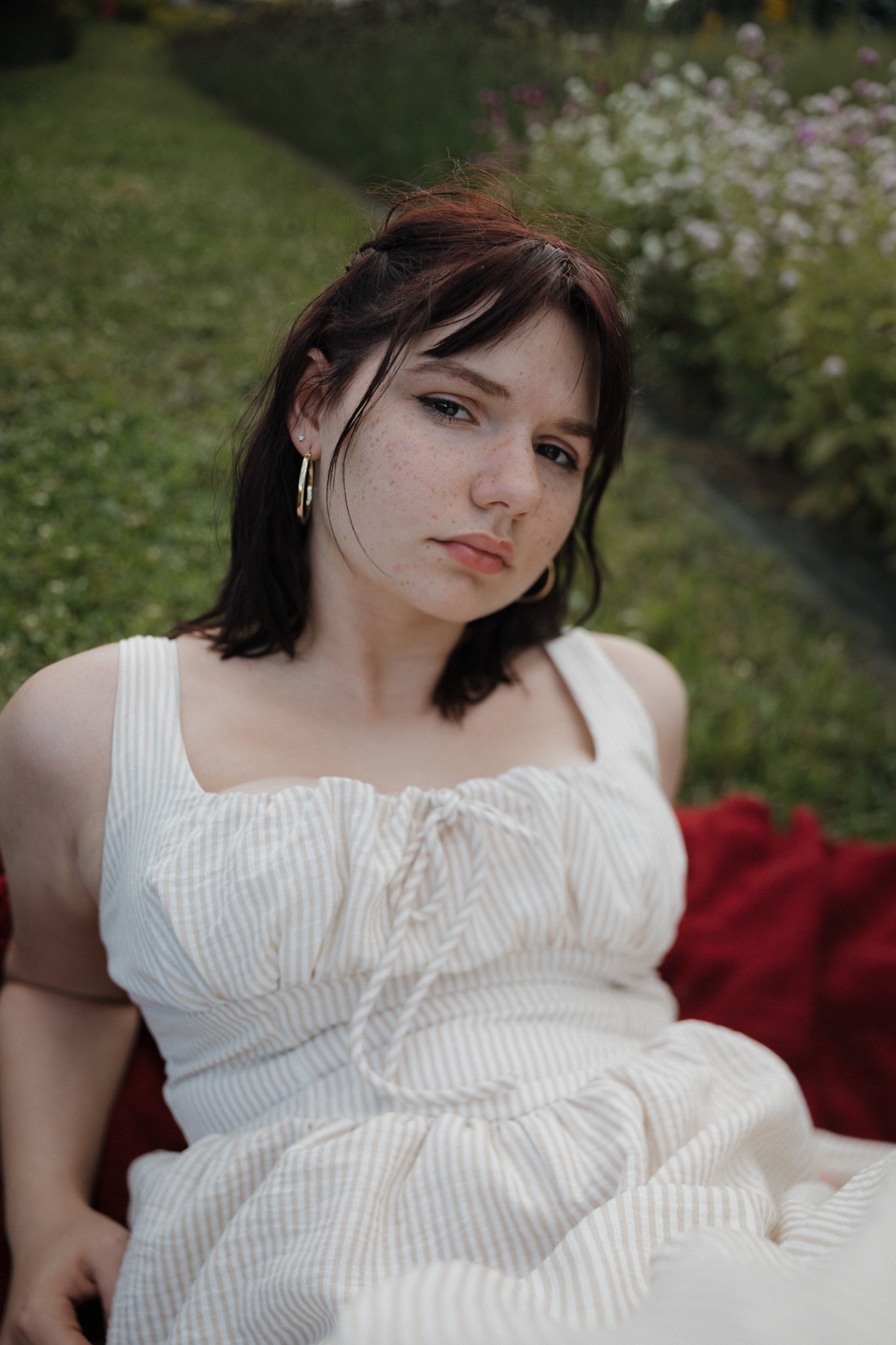 Person in white dress reclining on blanket outdoors.