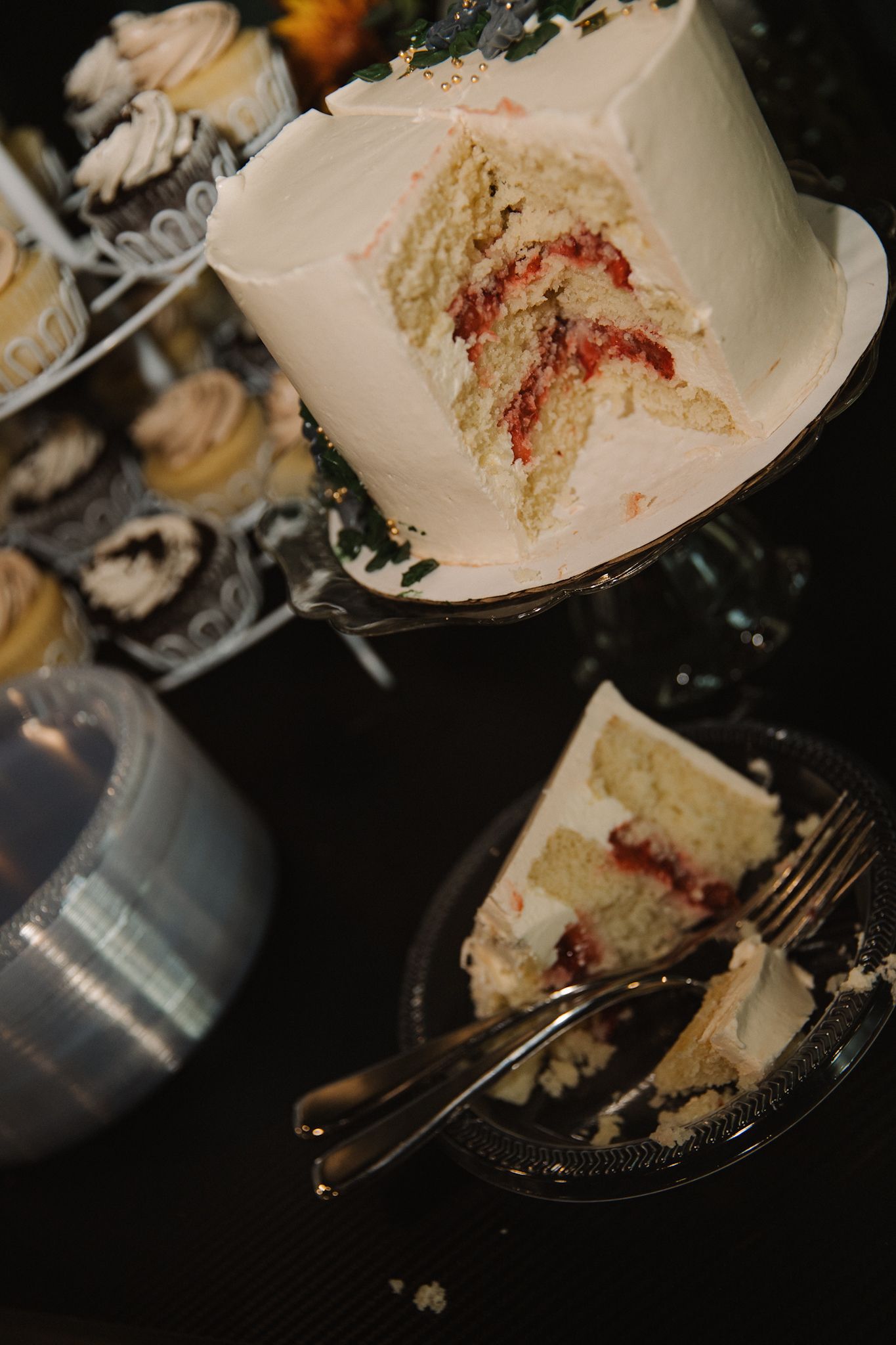 Half-eaten slices of white wedding cake with red filling on dark plates.