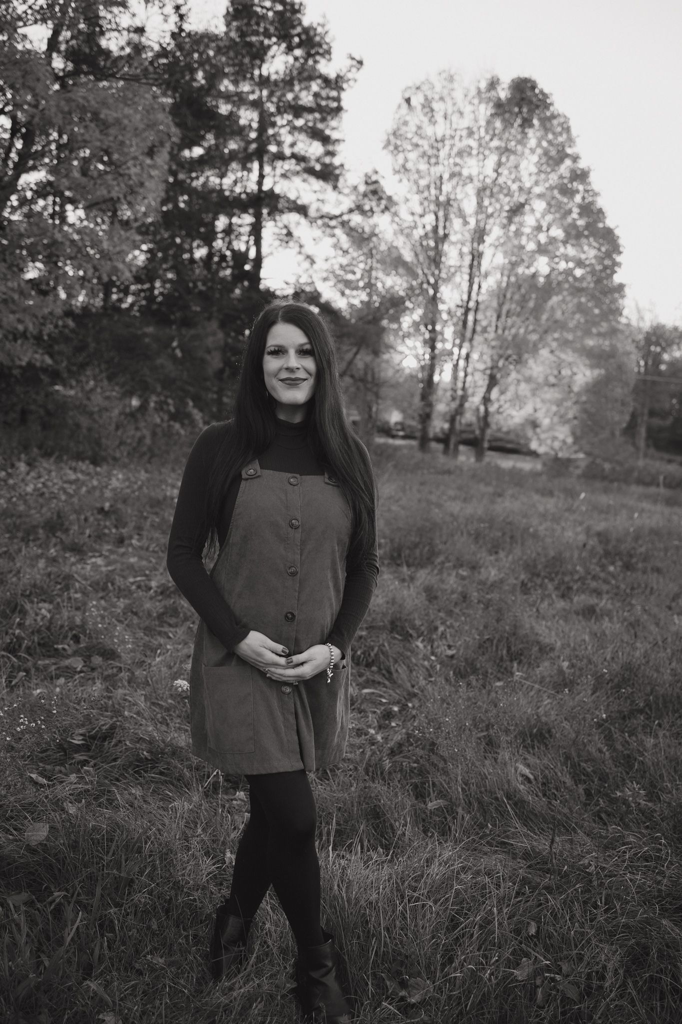 Black and white outdoor portrait series showing person in dark clothing standing in a grassy field with trees in background.