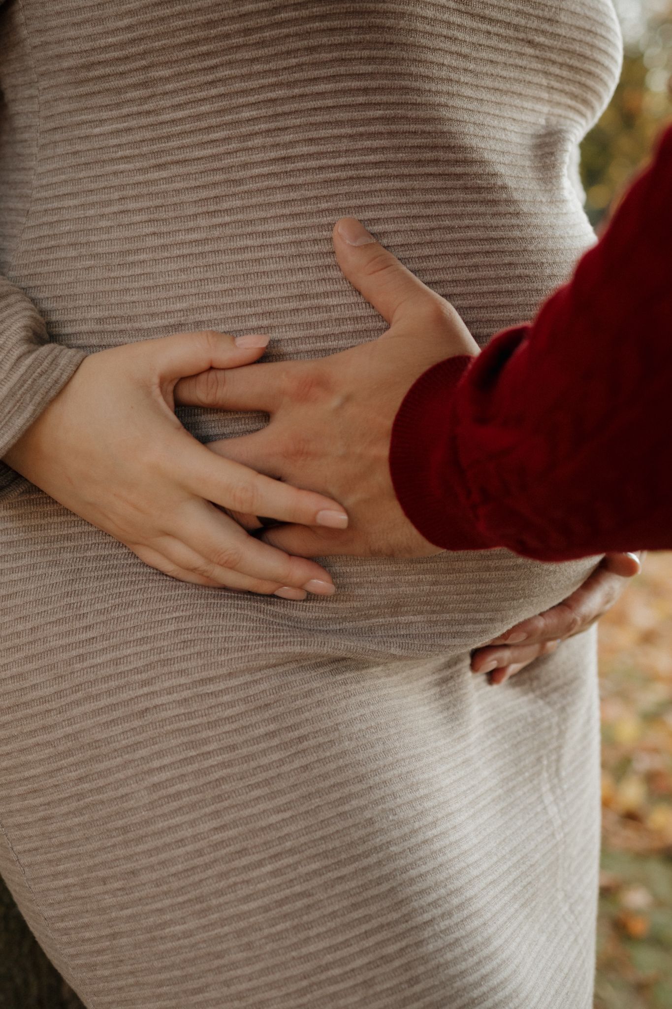 A series of photos showing hands gently cradling a pregnant belly covered in a soft gray ribbed sweater.