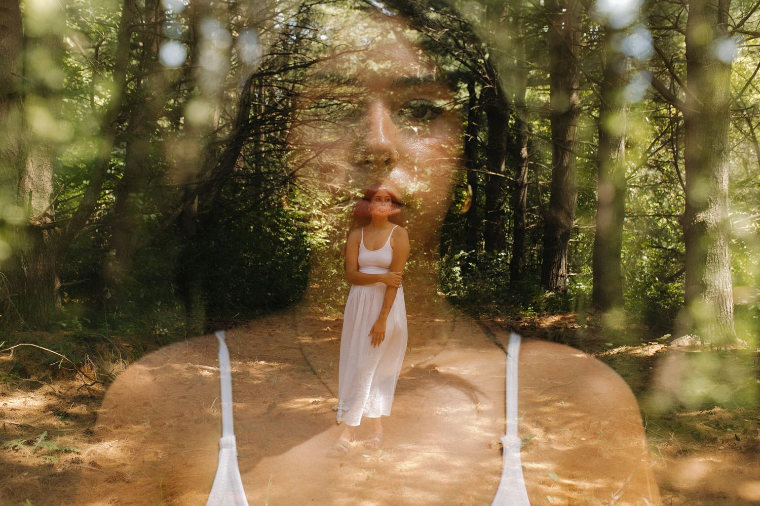 A dreamy multiple exposure photograph shows a person in white dress walking through a sunlit forest path.