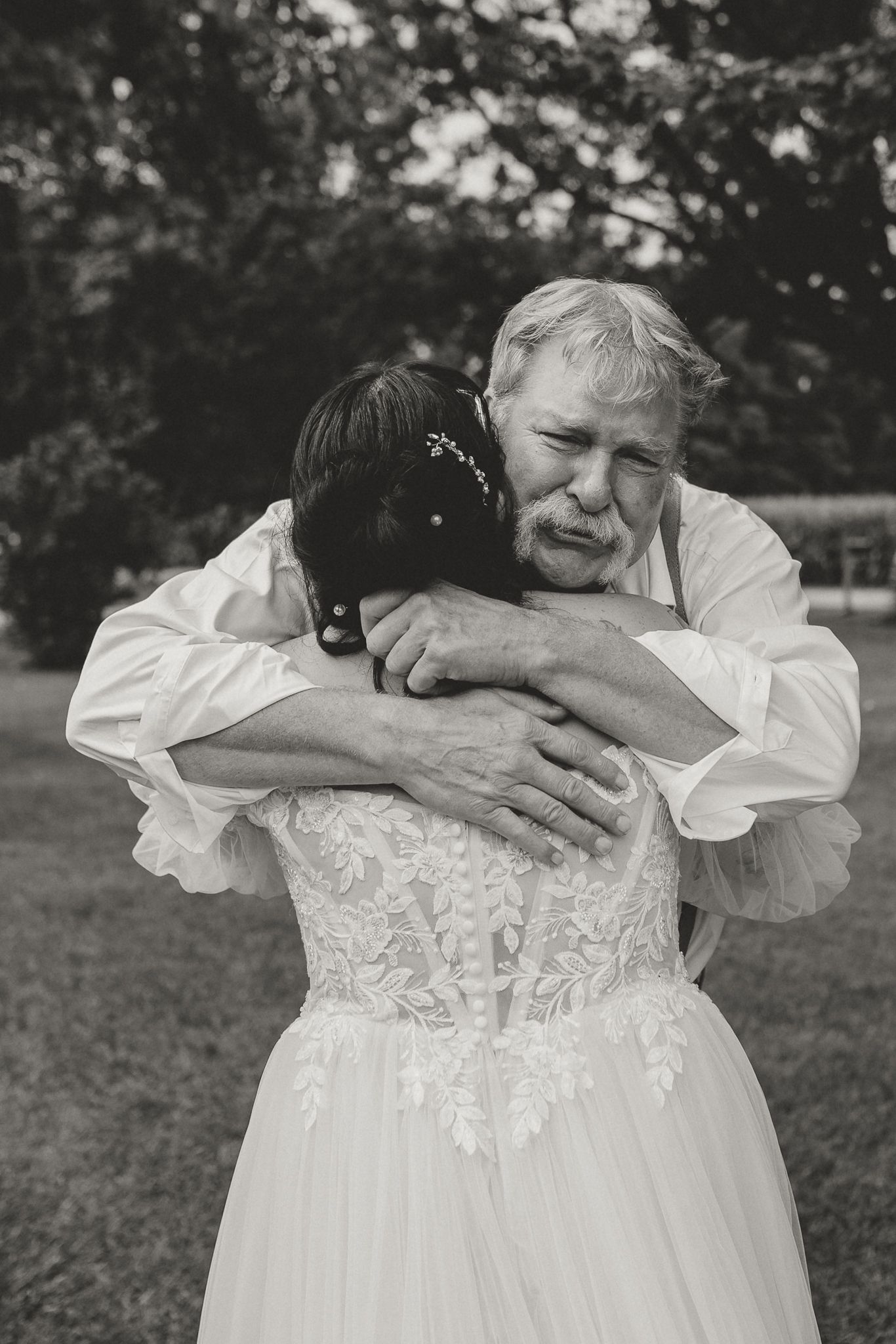 A black and white photo series showing two people in white dresses embracing and laughing together outdoors.