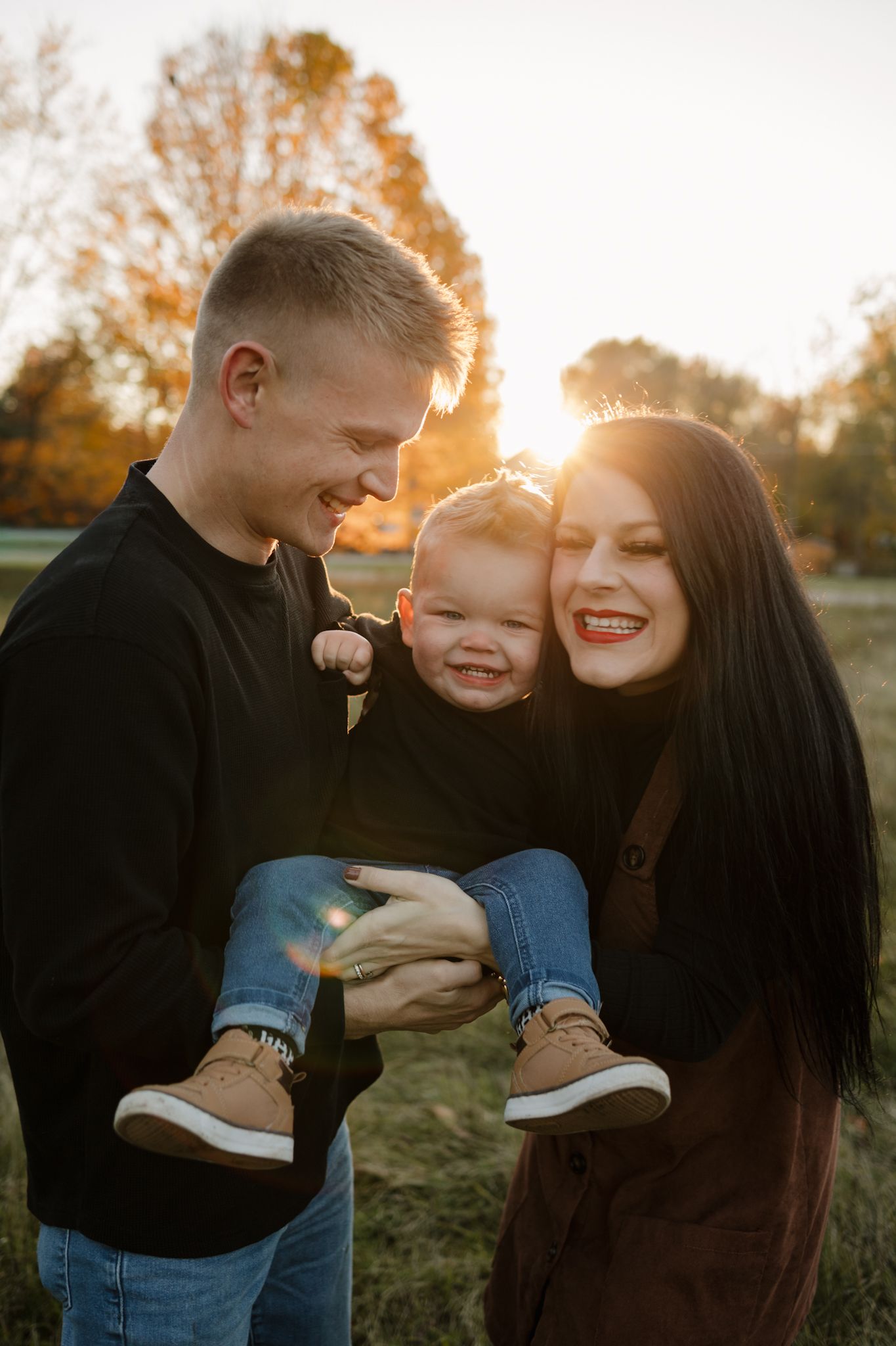 Family shares joyful embrace outdoors during golden hour sunset photoshoot in autumn.