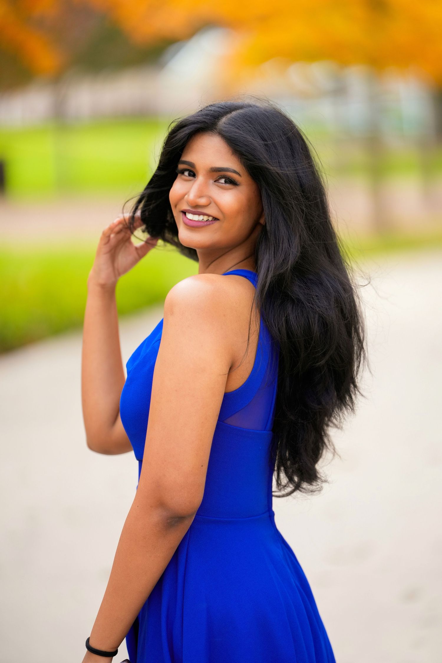 Natural light portrait of a smiling woman in a blue dress during an outdoor photography session.