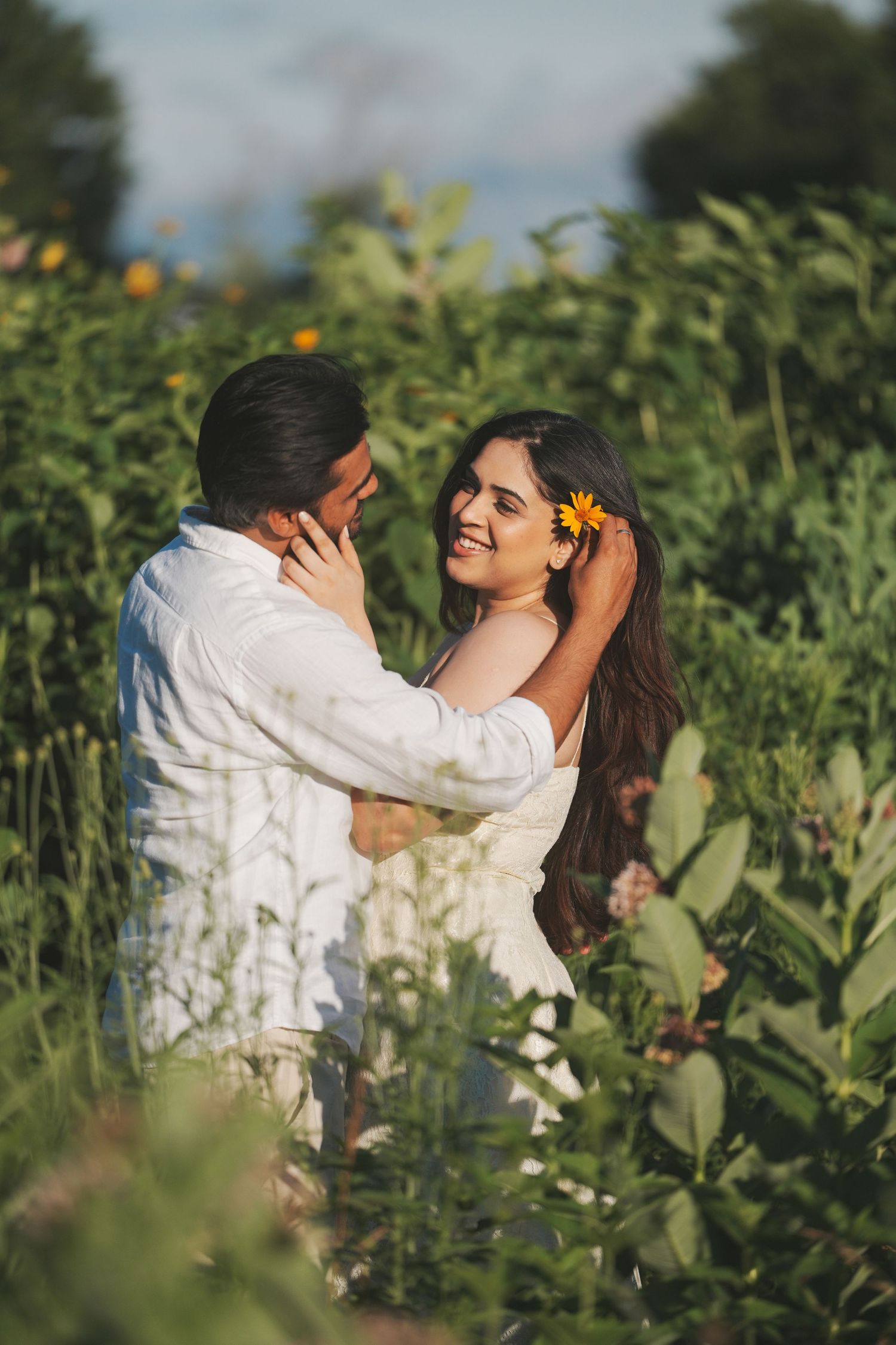 Romantic engagement photo of a couple surrounded by greenery, captured during golden hour.