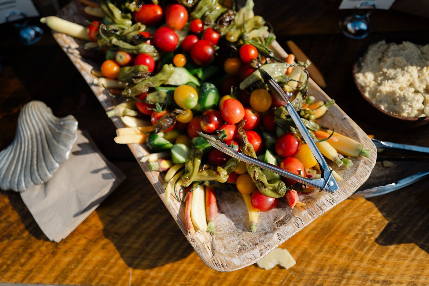 Colorful fresh vegetable crudite platter with cherry tomatoes and assorted veggies at a wedding reception.