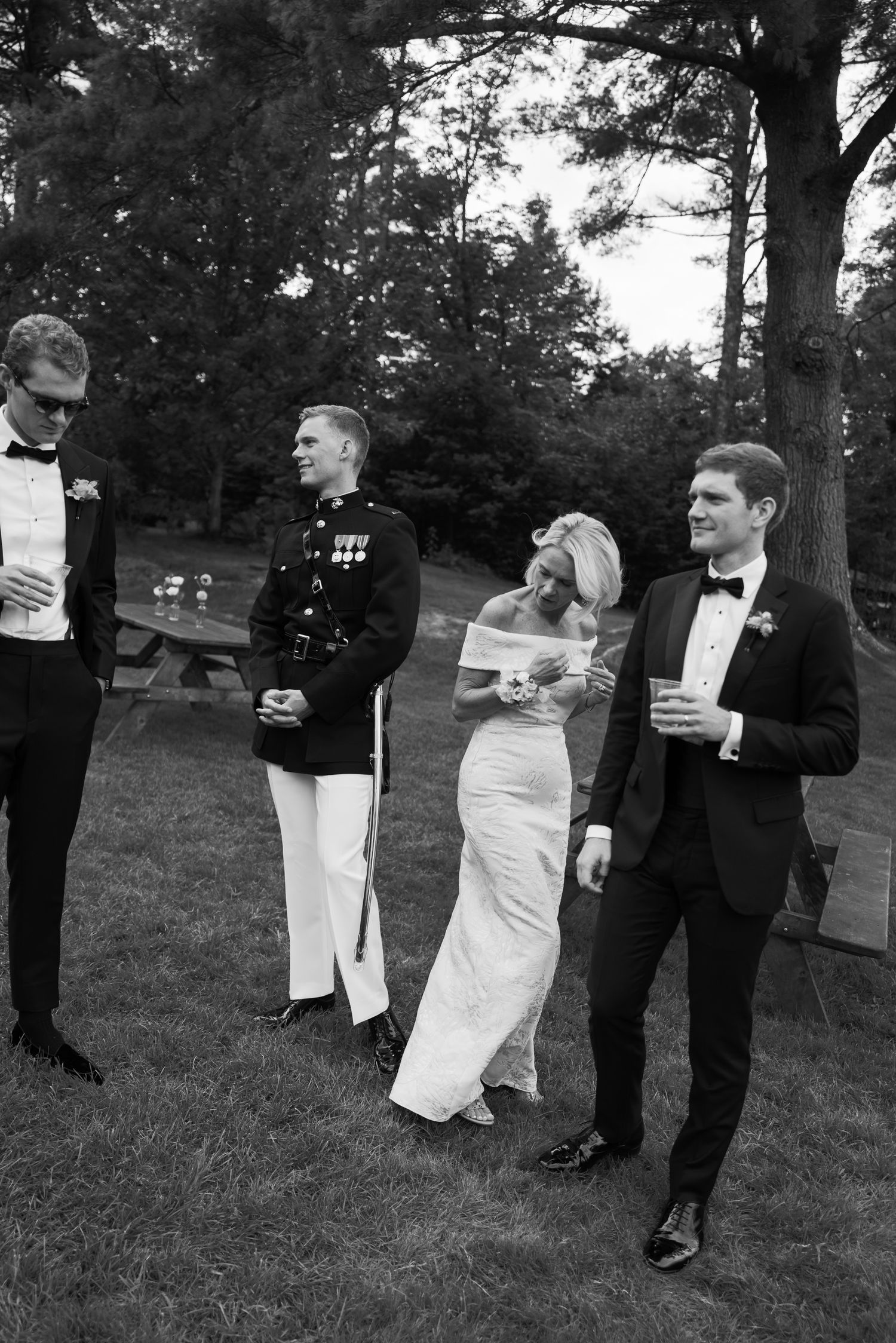 Black and white photo of wedding party mingling outdoors.