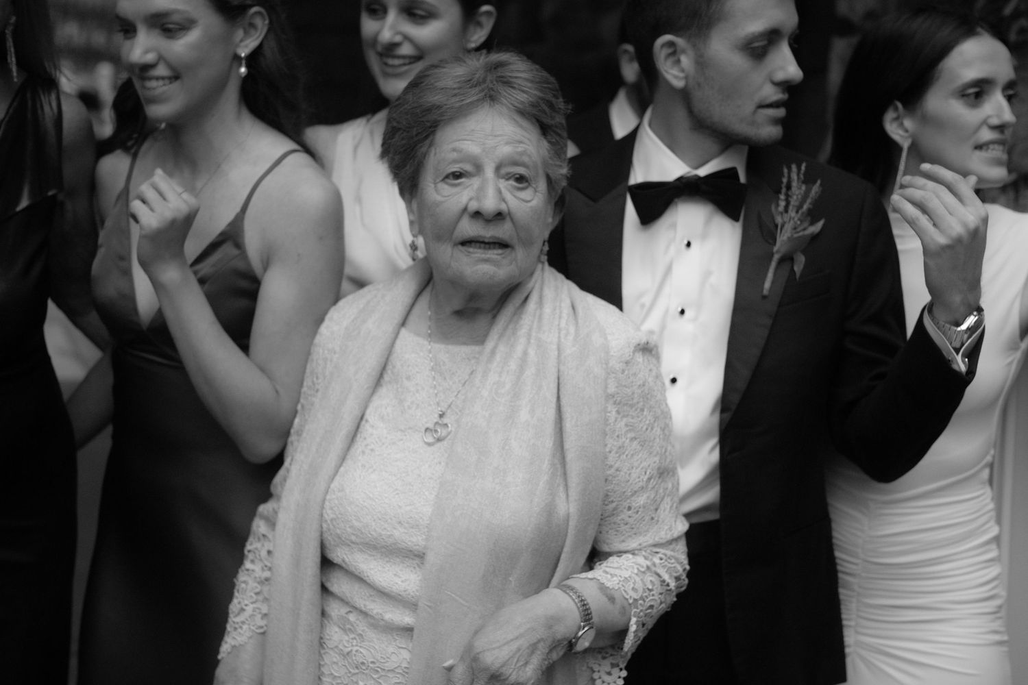 Elderly woman in elegant white dress and shawl at a formal event, black and white photo.