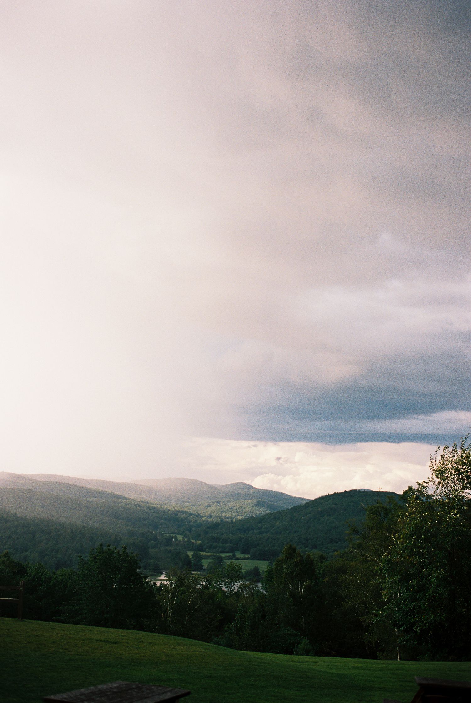 A dramatic cloudy sky over lush green rolling hills and mountains in a scenic landscape photo.