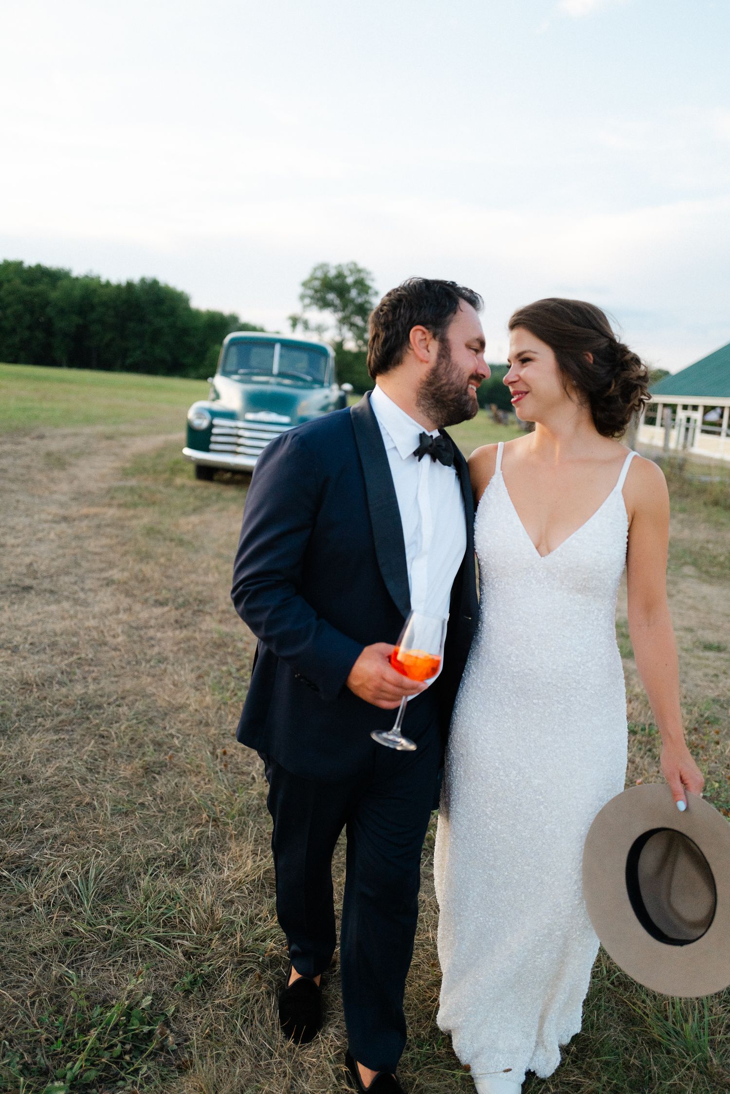 Bride and groom share romantic moment near vintage teal Chevrolet truck at outdoor wedding.