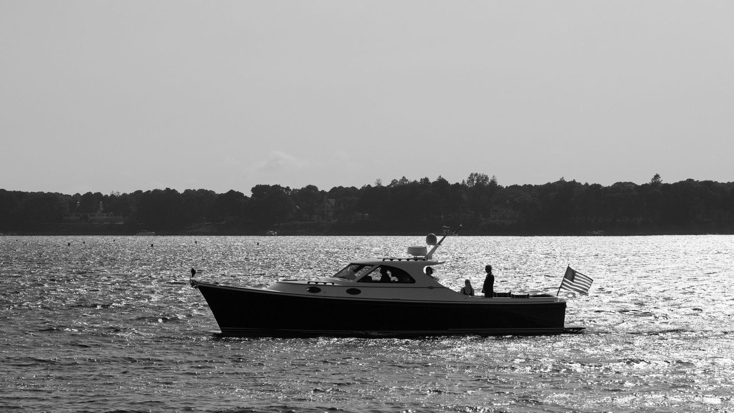 Classic motor yacht sailing on calm water in black and white nautical photo.