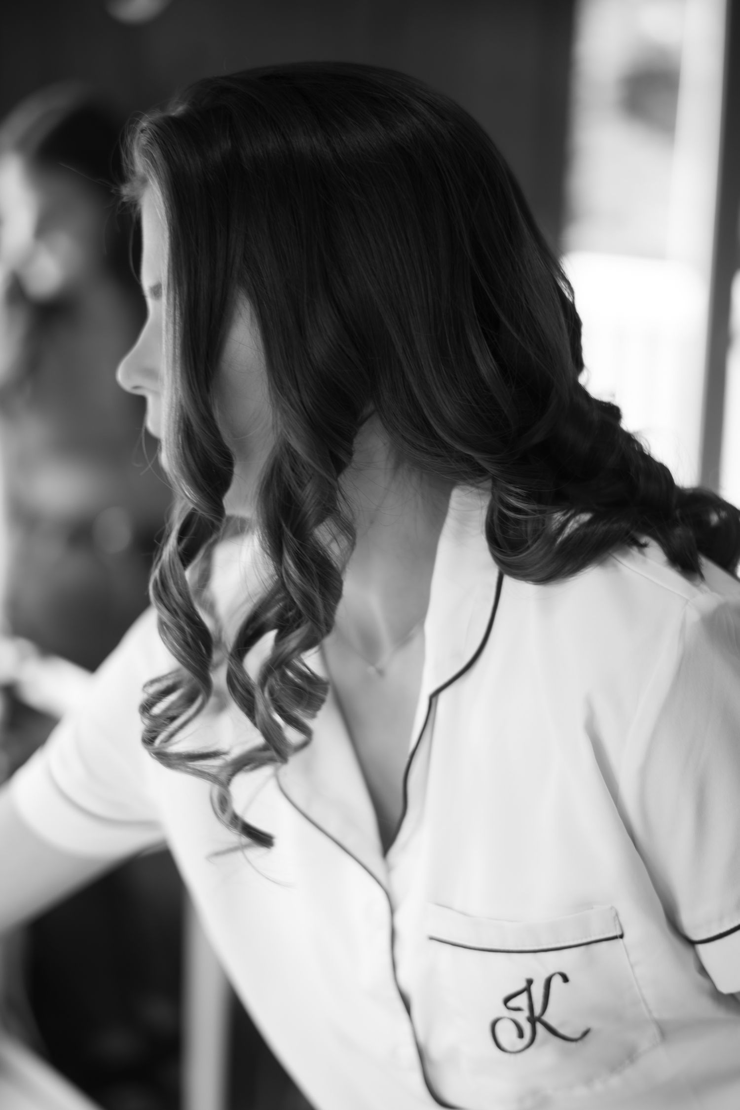 Black and white portrait of brunette bride in monogrammed white pajamas.