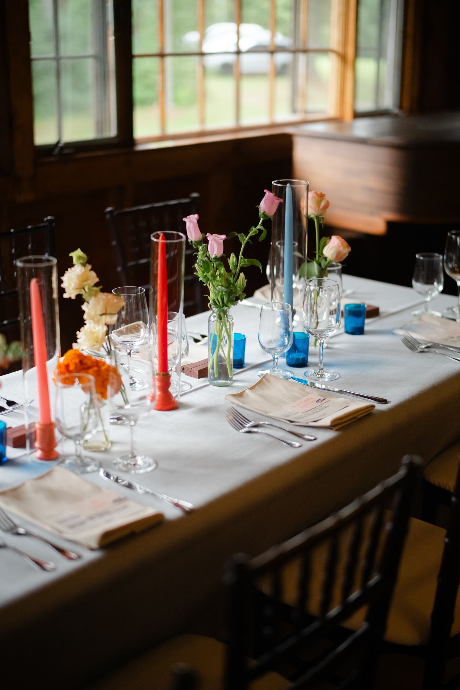 Elegant wedding reception table set with colorful candles and fresh flower arrangements.