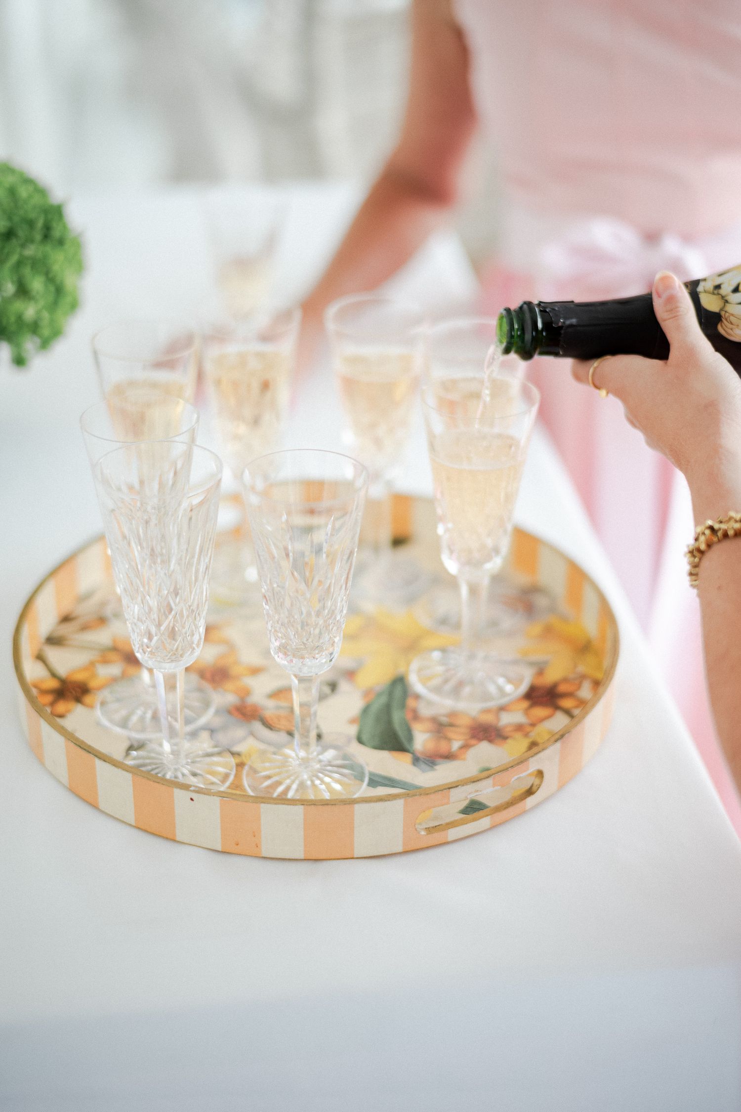 Champagne being poured into crystal flutes on a decorative striped tray at a wedding reception.