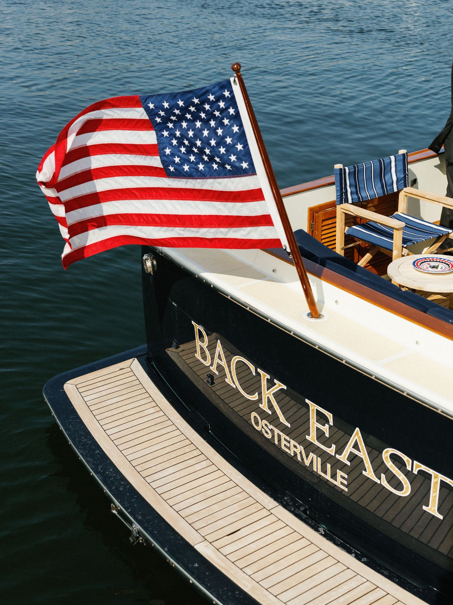 Stern of Back East Osterville classic wooden boat with American flag flying proudly.
