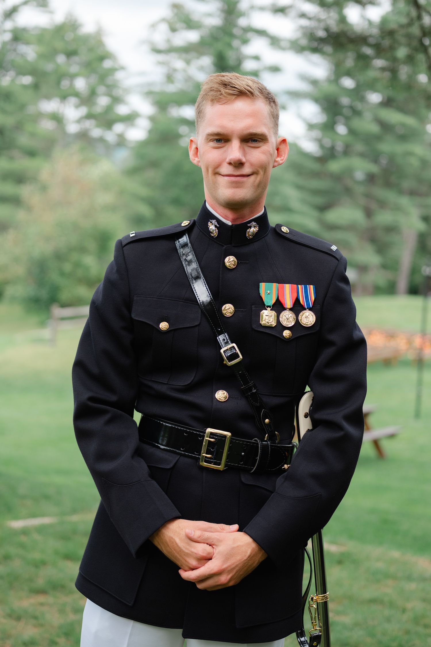Smiling Marine officer in dress blues uniform outdoors.