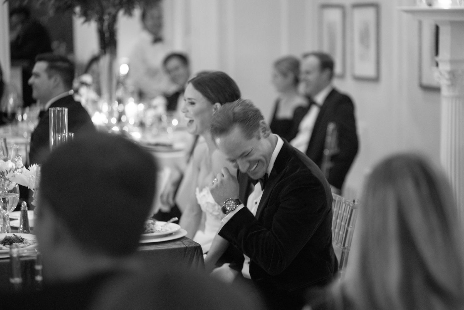 Black and white photo of bride and groom sharing an emotional moment during wedding reception speeches.