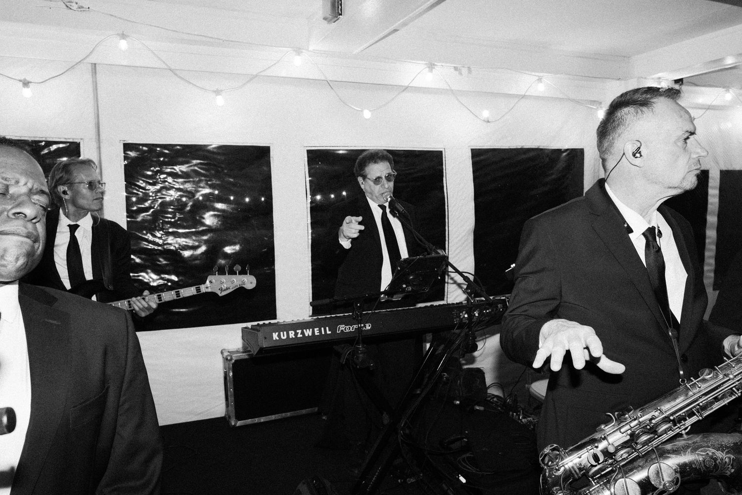 Black and white photo of live band performing at wedding reception with keyboard and saxophone players.