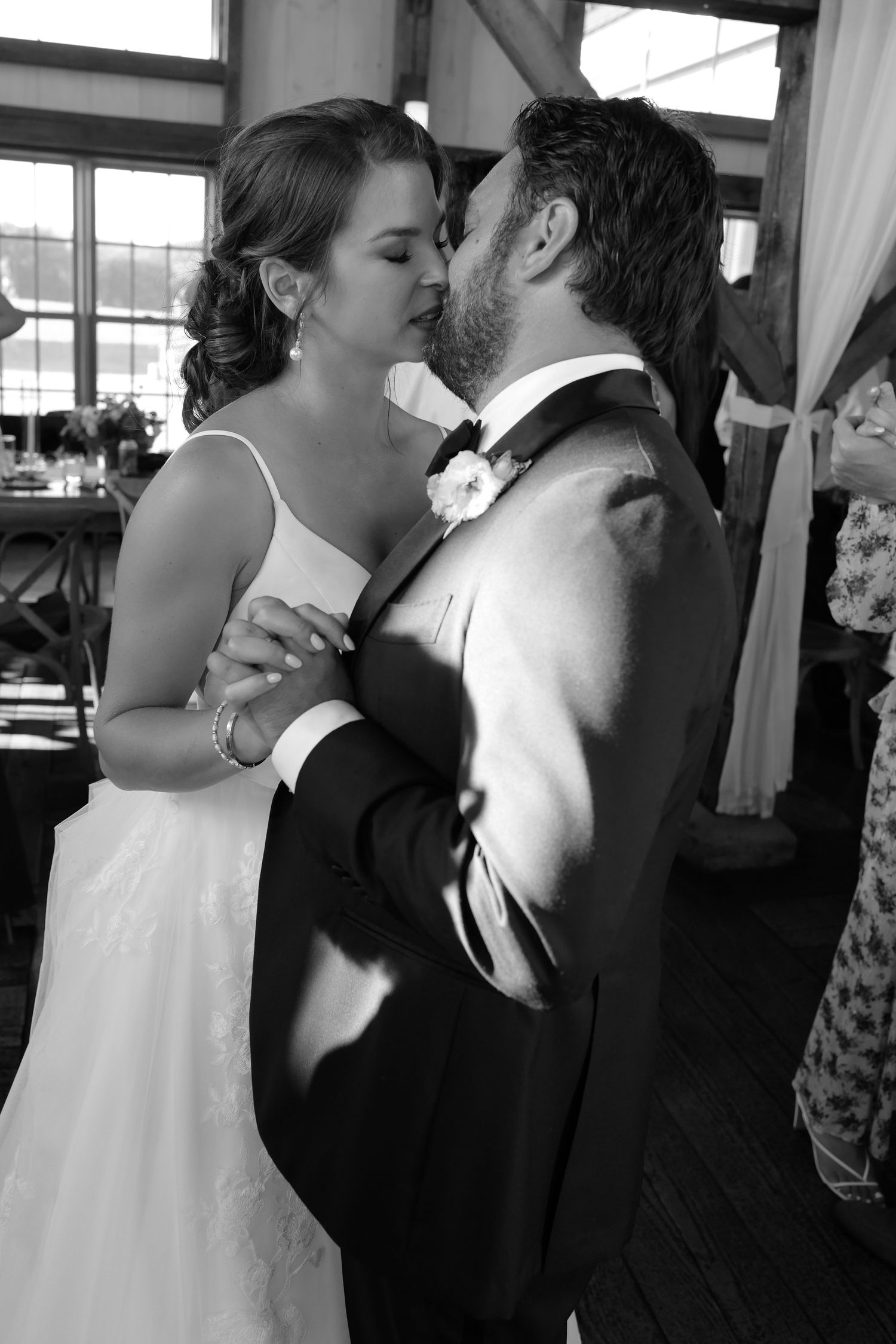 Bride and groom share a romantic kiss during their first dance at an elegant indoor wedding reception.