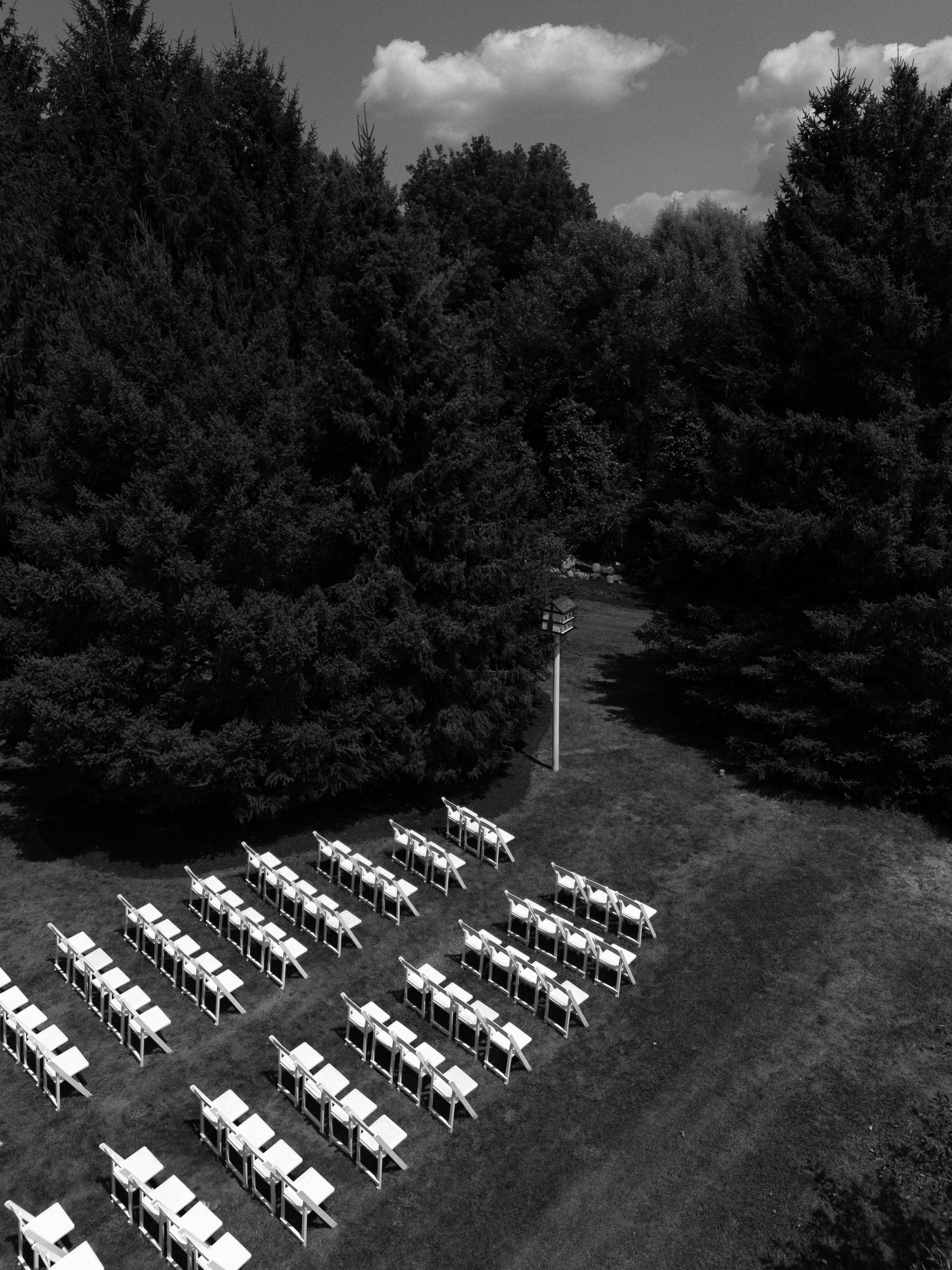Aerial black and white view of white chairs arranged in rows for an outdoor wedding ceremony.