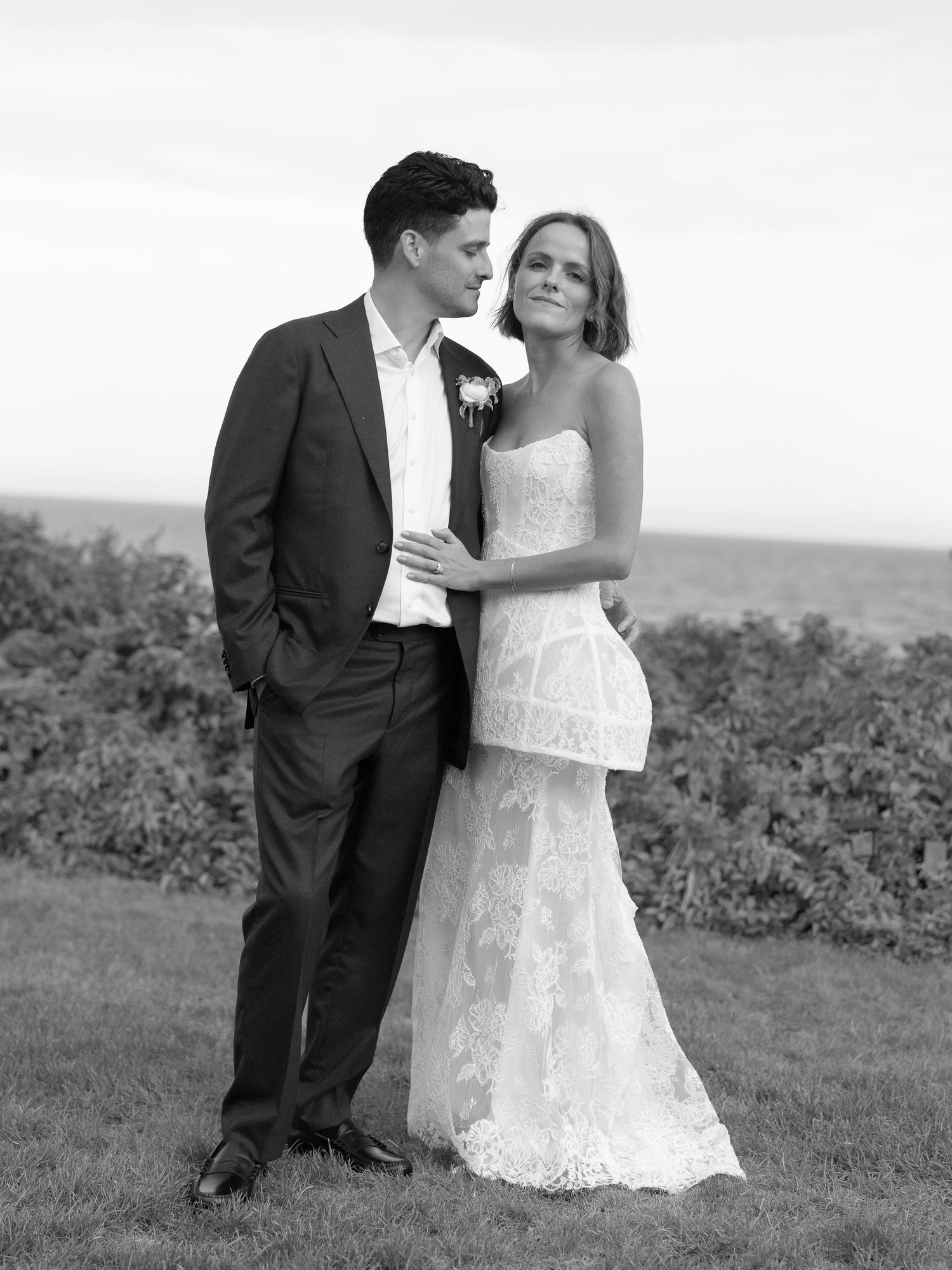 Black and white portrait of bride and groom embracing outdoors on wedding day.