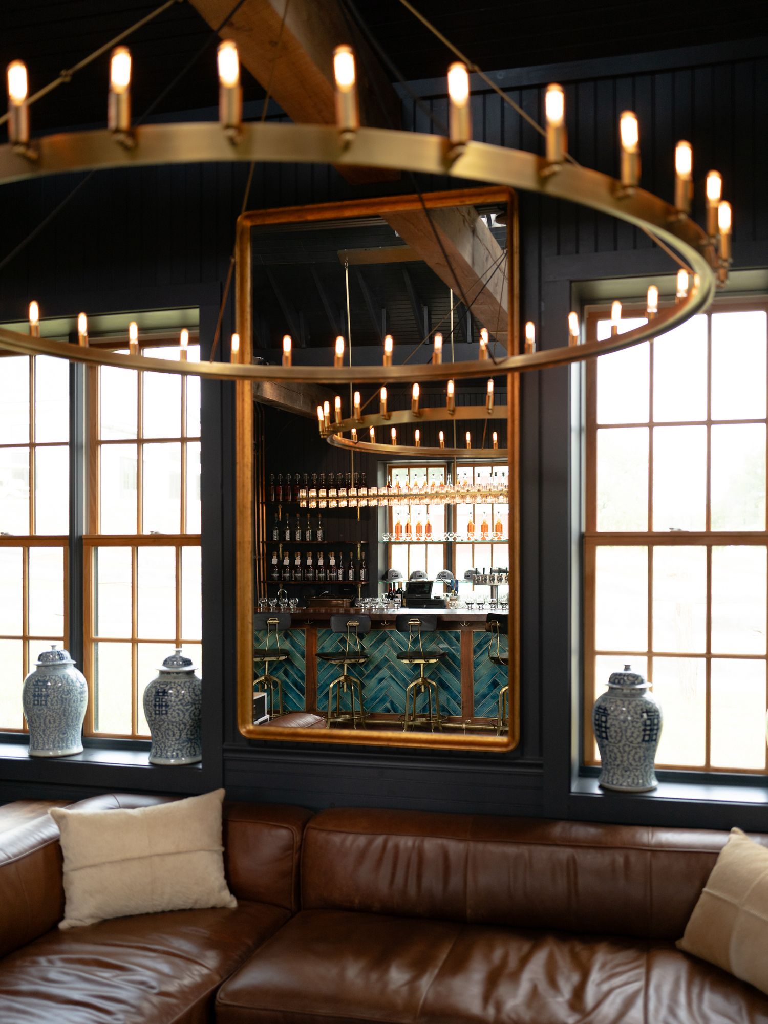 Elegant bar lounge with circular candle chandelier and large gold mirror.