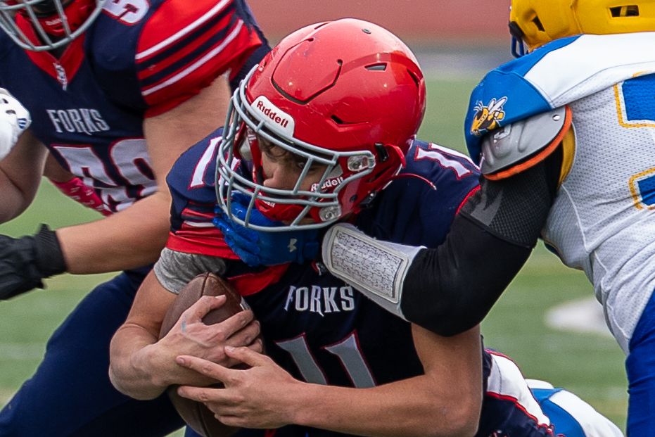 Varsity football player powers through a tackle during a New York State Public High School Athletic Association Section championship game.