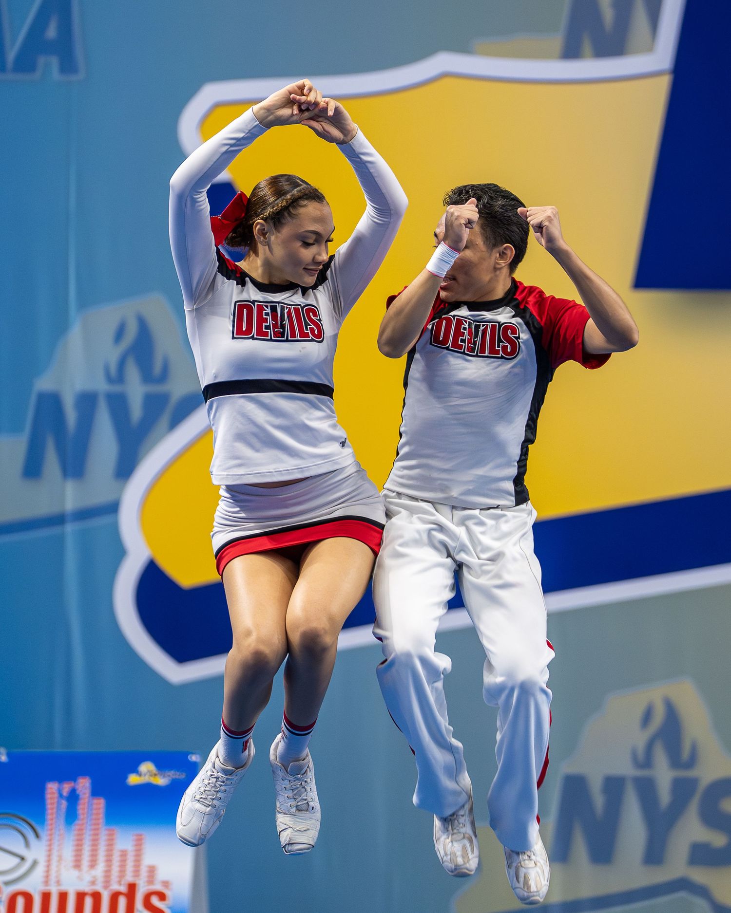 High school cheerleaders perform during a NYSPHSAA championship competition showcasing athleticism and teamwork.