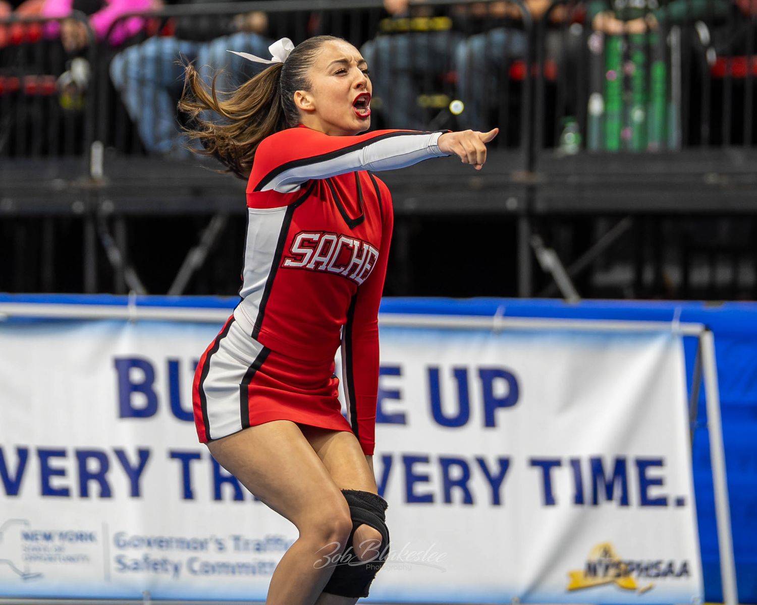 Sachem cheerleader in red uniform performs an energetic routine at the NYSPHSAA Championships.