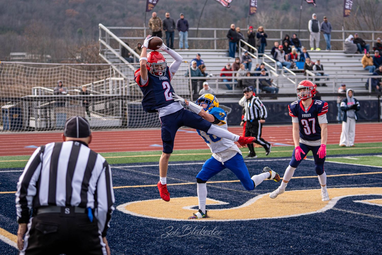 Football player in blue jersey leaps to catch a pass in the end zone during a playoff game.