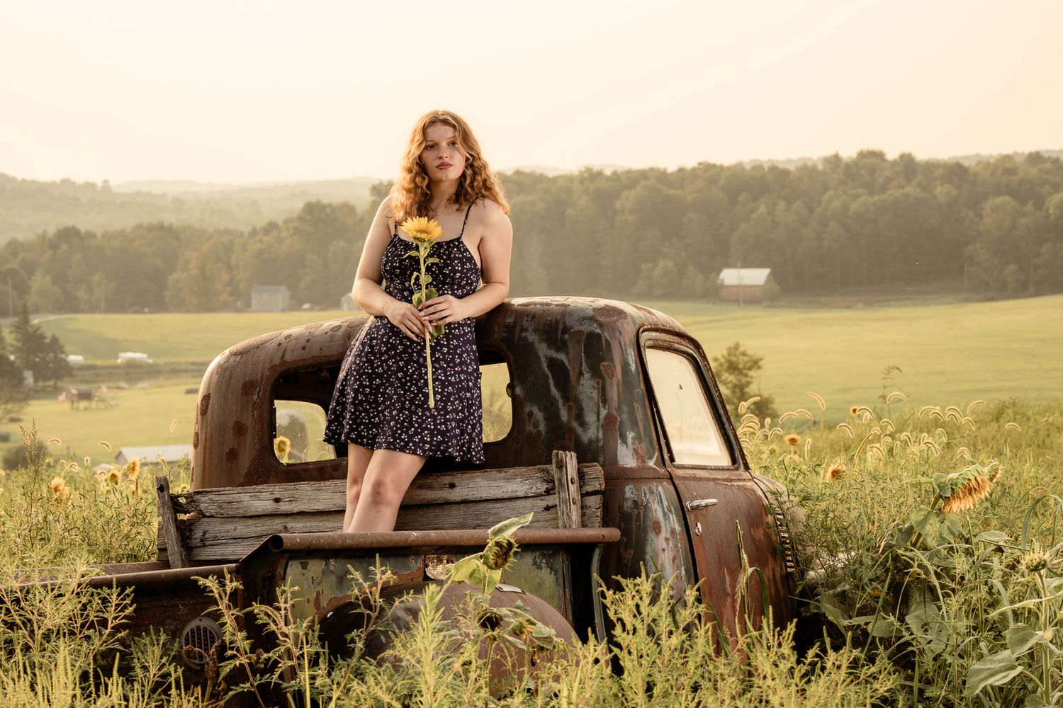 girl senior portrait at sunflower farm, sunset in background, golden hour, while standing on a vintage pickup truck