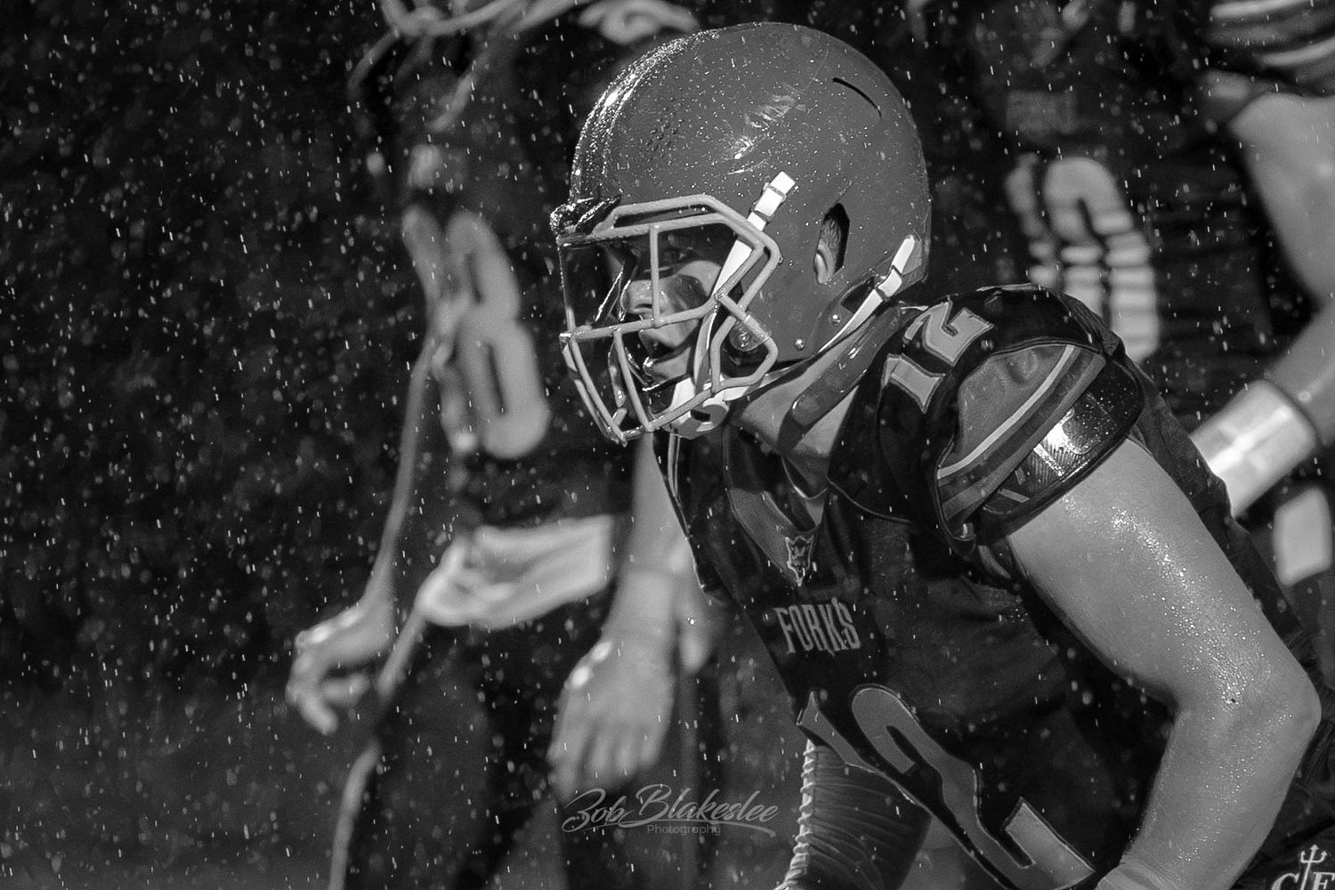 Black and white portrait of a high school football player standing in the rain during a varsity game in Chenango Forks, NY.