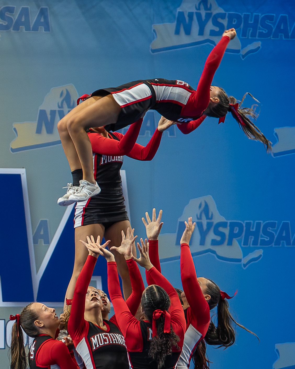 High school cheerleaders perform a championship stunt during a NYSPHSAA competition captured by a Section IV sports photographer.