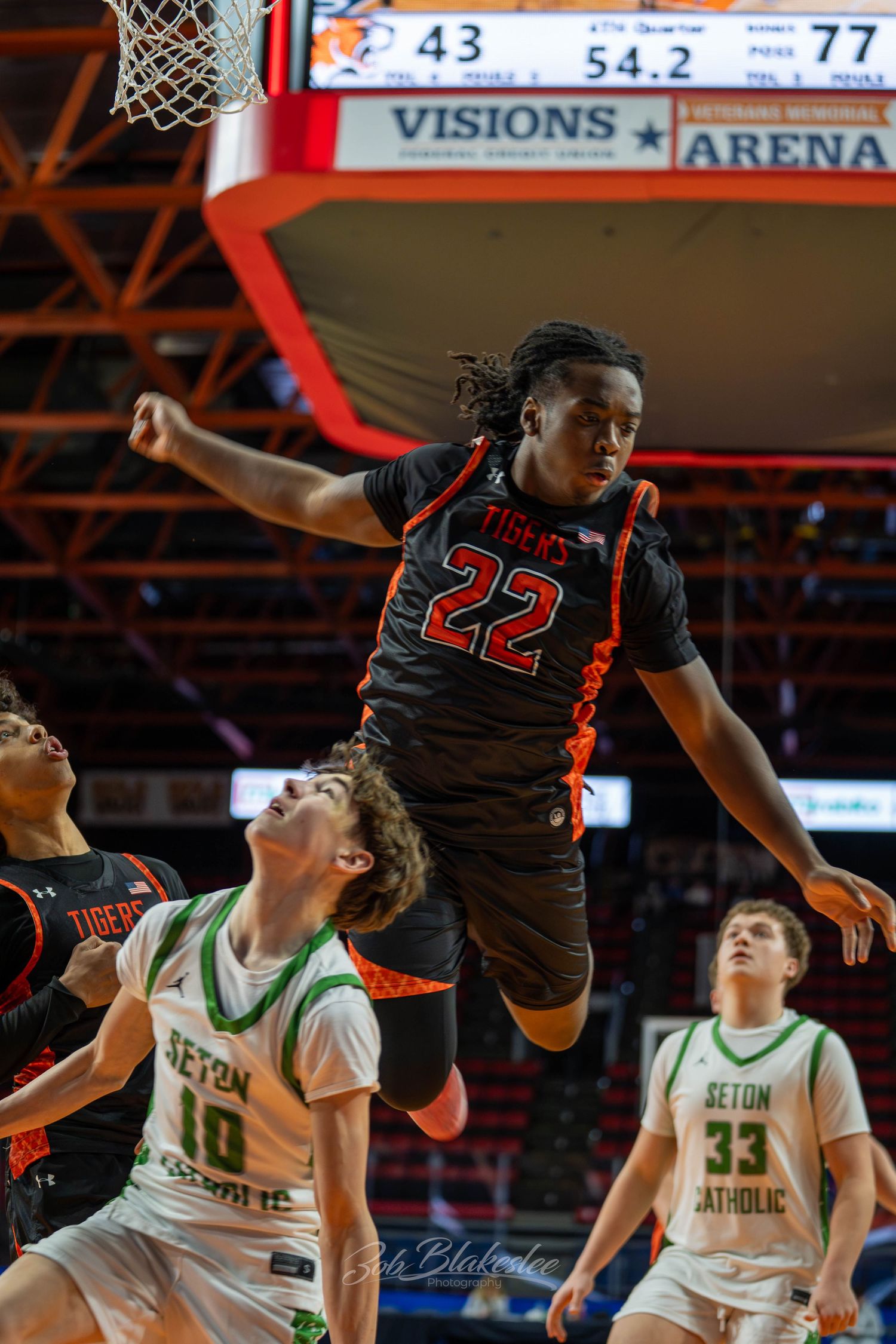 Player #22 in black Tigers jersey leaps for a dunk at Visions Veterans Memorial Arena basketball game.