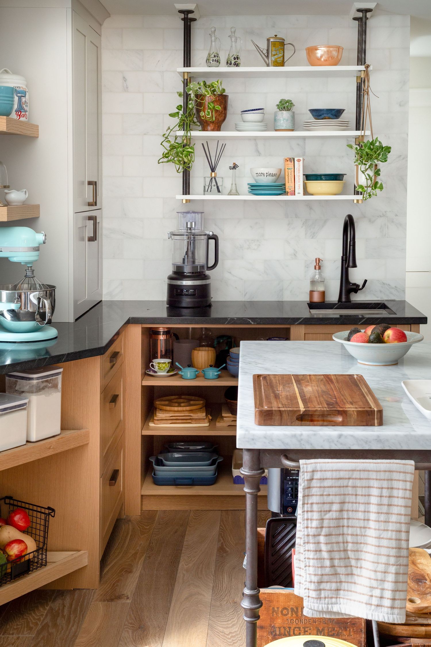 Modern kitchen with open shelving, marble backsplash, wood cabinets, and island with cutting board.