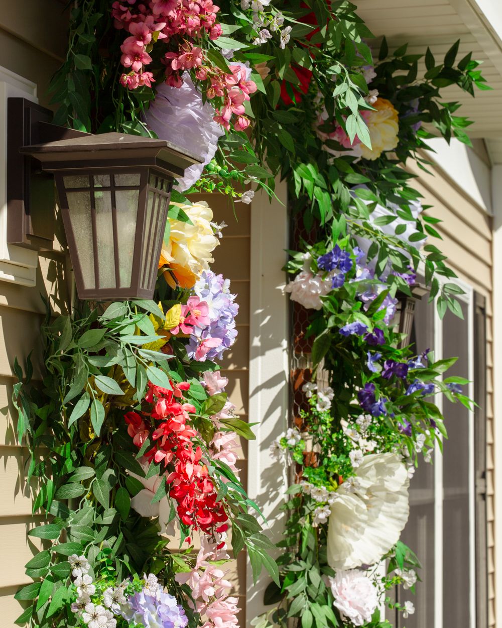 Colorful spring floral garland with pink, purple, and red flowers framing a home entrance lantern.