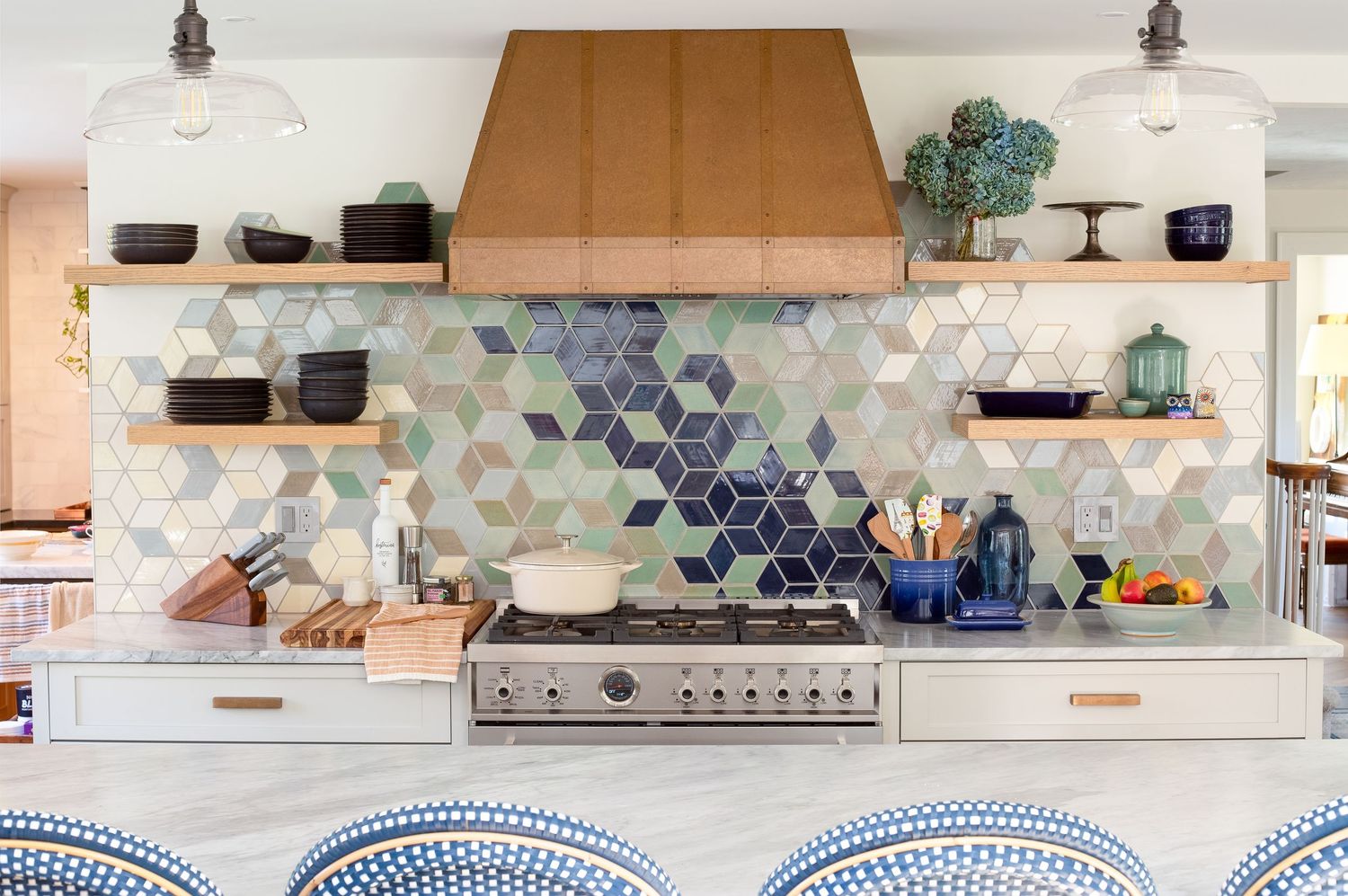 Kitchen with geometric diamond tile backsplash, copper hood, open shelves, and marble island.