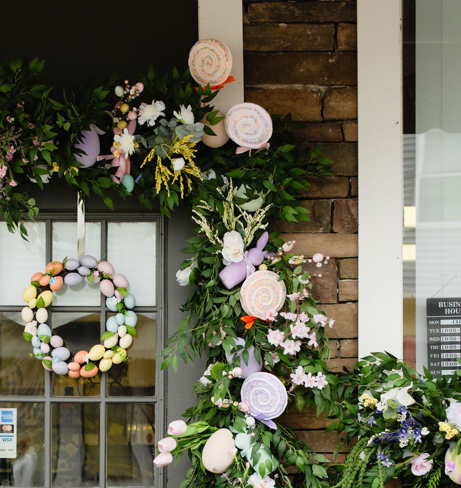 Festive Easter porch display featuring egg wreaths, pastel lollipop decorations, and spring florals.