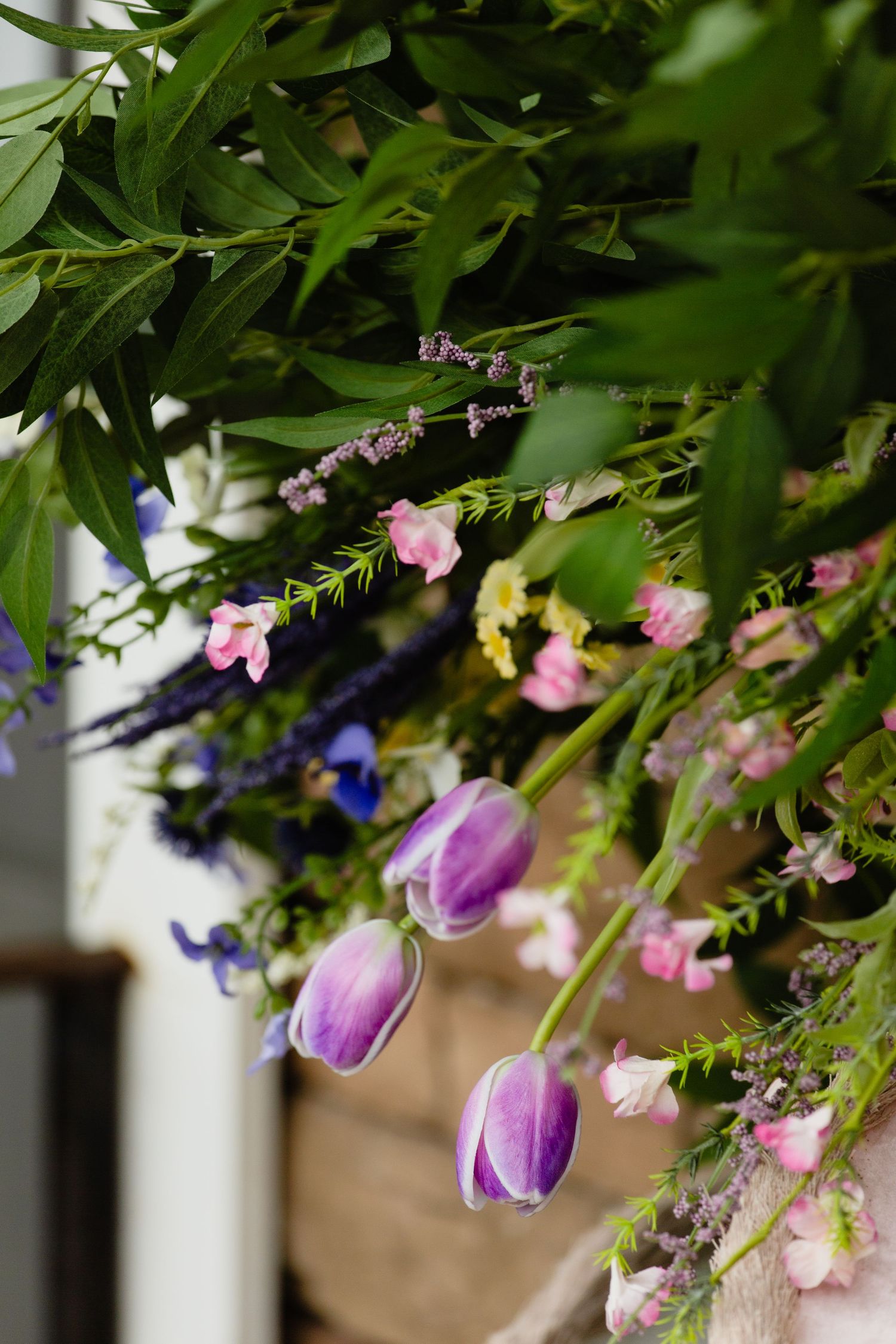 Close-up of purple tulips, pink flowers, and lavender in a lush spring floral arrangement.